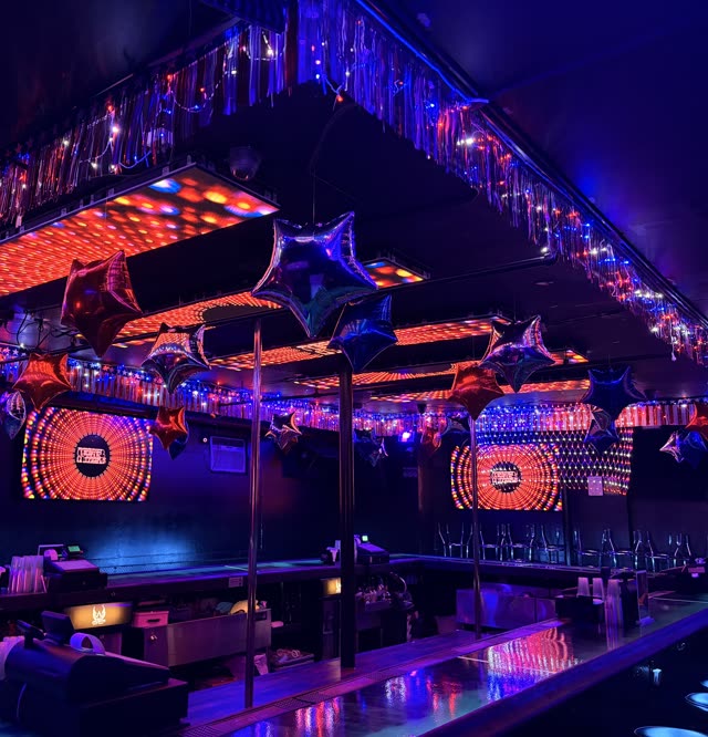 The ceiling over the bar dressed with foil star balloons, red, white and blue fringe and string lights, the LED panels lit behind them.